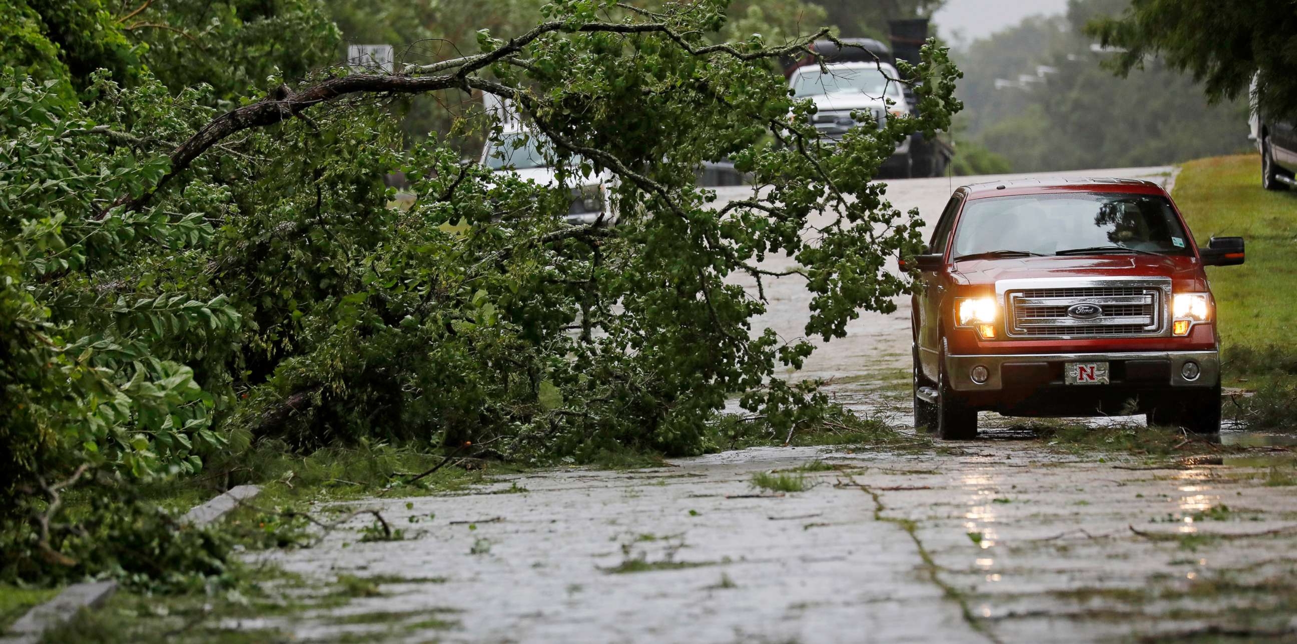 PHOTO:A truck maneuvers around a downed tree after strong wind gusts dropped it in west Morgan City, La., July 13, 2019.