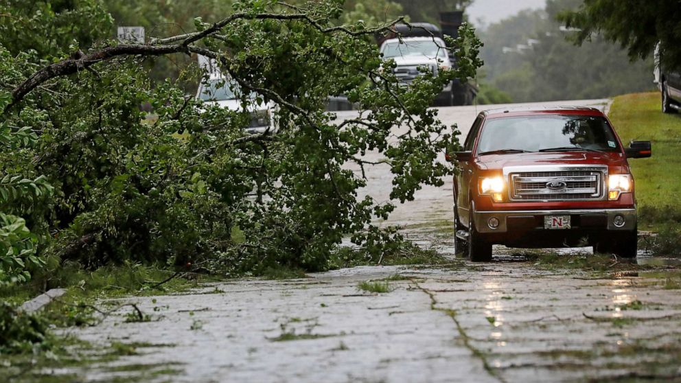 PHOTO:A truck maneuvers around a downed tree after strong wind gusts dropped it in west Morgan City, La., July 13, 2019.