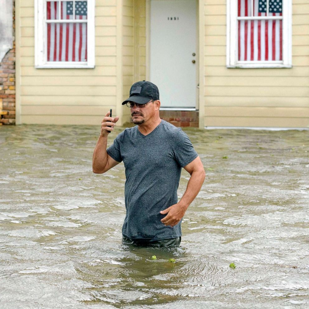 PHOTO: A man talks on his smartphone as he wades through storm surge from Lake Pontchartrain on Lakeshore Drive in Mandeville, La., as Hurricane Barry approaches, July 13, 2019.