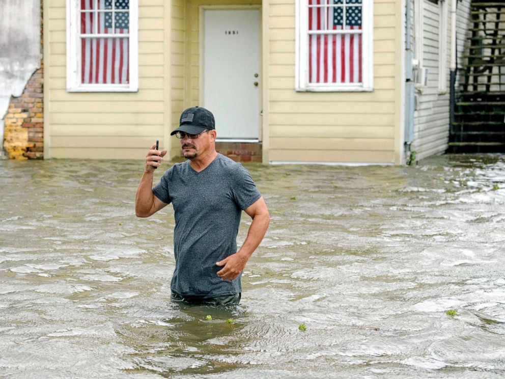 PHOTO: A  man talks on his smartphone as he wades through storm surge from Lake Pontchartrain on Lakeshore Drive in Mandeville, La., as Hurricane Barry approaches, July 13, 2019. 