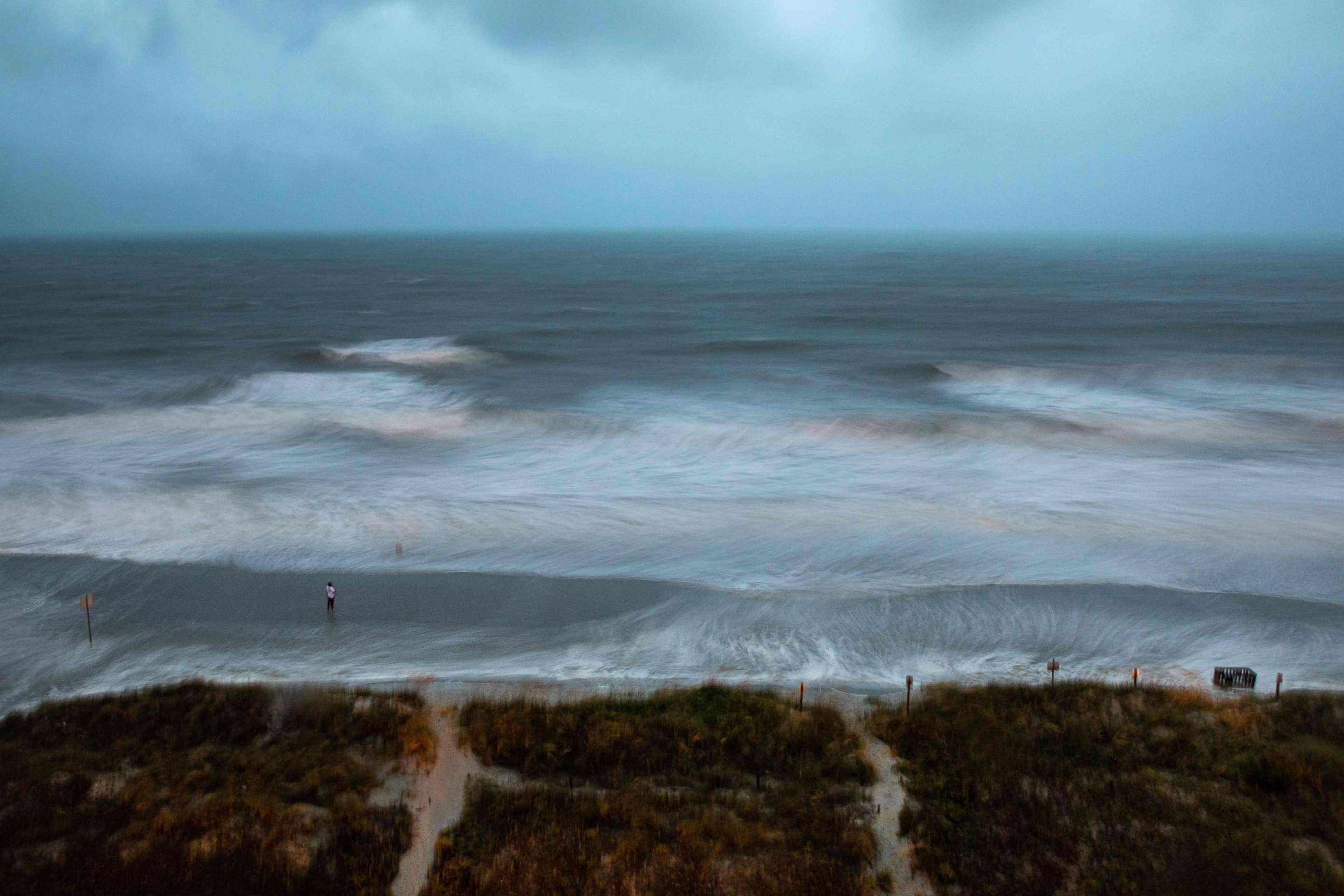 PHOTO: Large surf is swirled by the wind and captured by a long exposure, while a person stands on the shore as Hurricane Isaias approaches North Myrtle Beach, SC on August 3, 2020. 