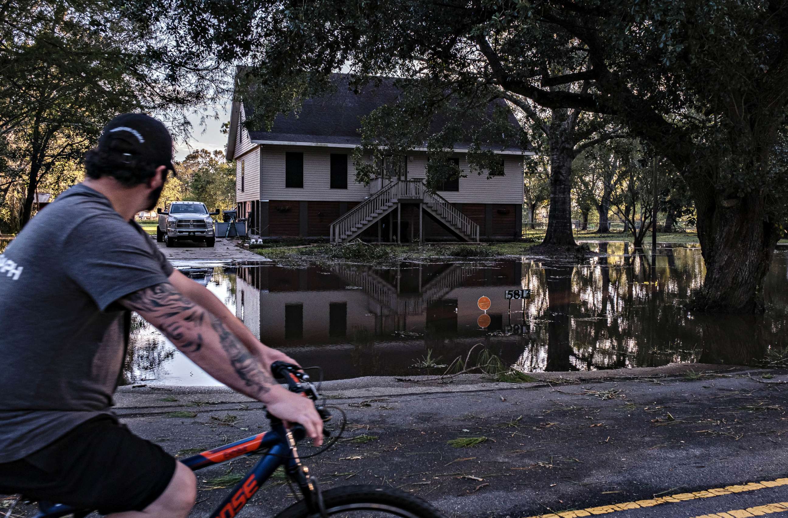 PHOTO: A man rides his bike by a yard flooded from Hurricane Delta in New Iberia, La., Oct. 10, 2020.