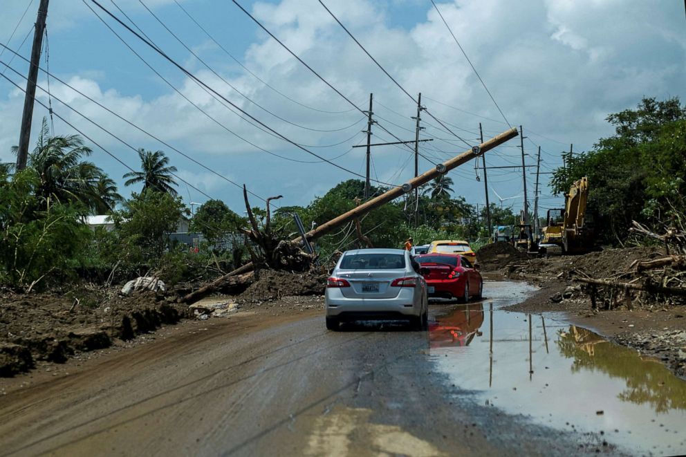 FILE PHOTO: Cars drive under a downed power pole in the aftermath of Hurricane Fiona in Santa Isabel, Puerto Rico September 21, 2022. 