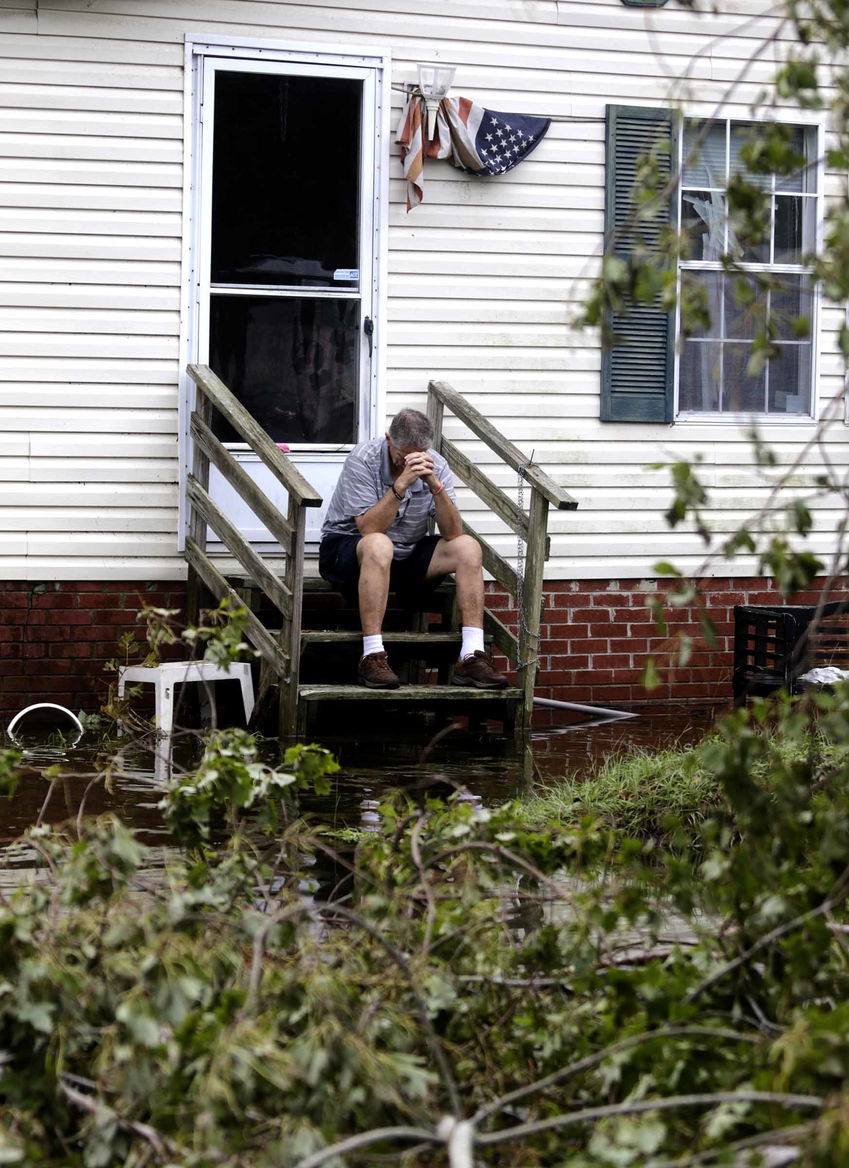 PHOTO: Joe Wiggins prays on the porch of his home surrounded by water after Hurricane Florence hit Emerald Isle N.C., Sept. 16, 2018.