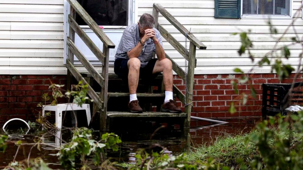 PHOTO: Joe Wiggins prays on the porch of his home surrounded by water after Hurricane Florence hit Emerald Isle N.C., Sept. 16, 2018.