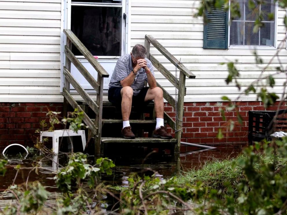 PHOTO: Joe Wiggins prays on the porch of his home surrounded by water after Hurricane Florence hit Emerald Isle N.C., Sept. 16, 2018.