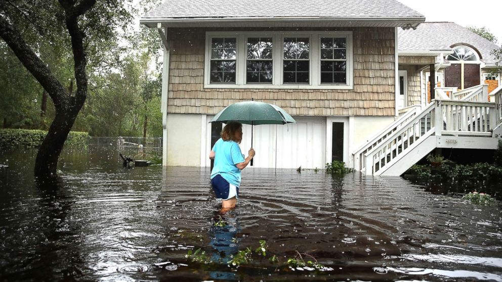 PHOTO: A woman makes her way to her home that is surrounded by flood waters after Hurricane Florence passed through the area on Sept. 15, 2018, in Southport, N.C.