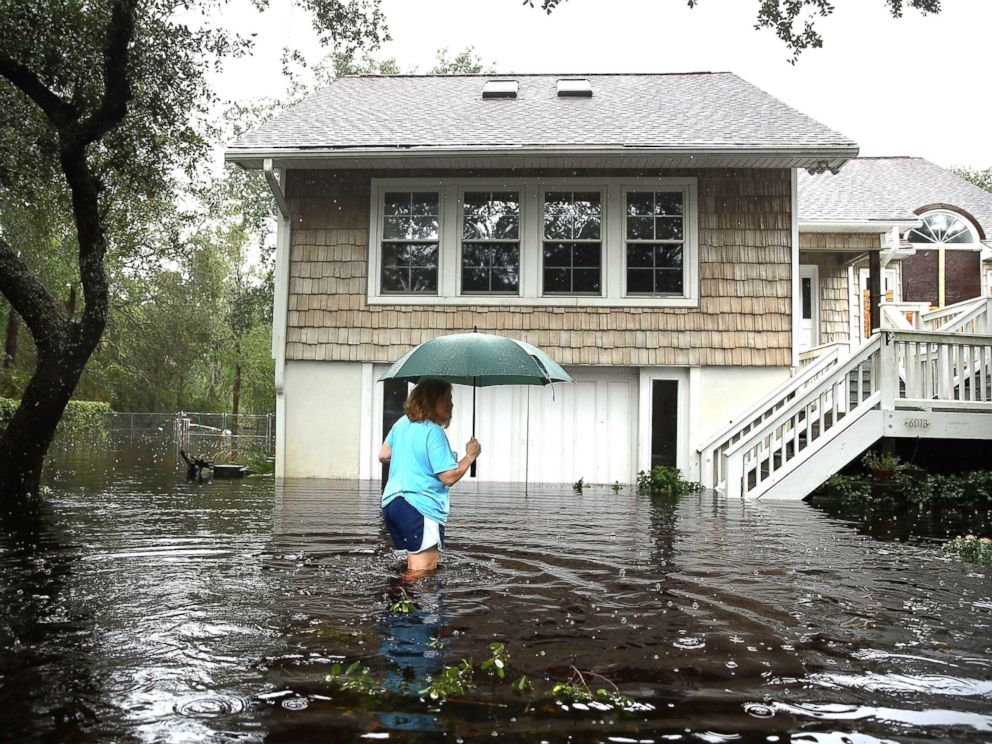 PHOTO: A woman goes to her home, surrounded by flood water, after the passage of Hurricane Florence in the area on September 15, 2018 in Southport, North Carolina.