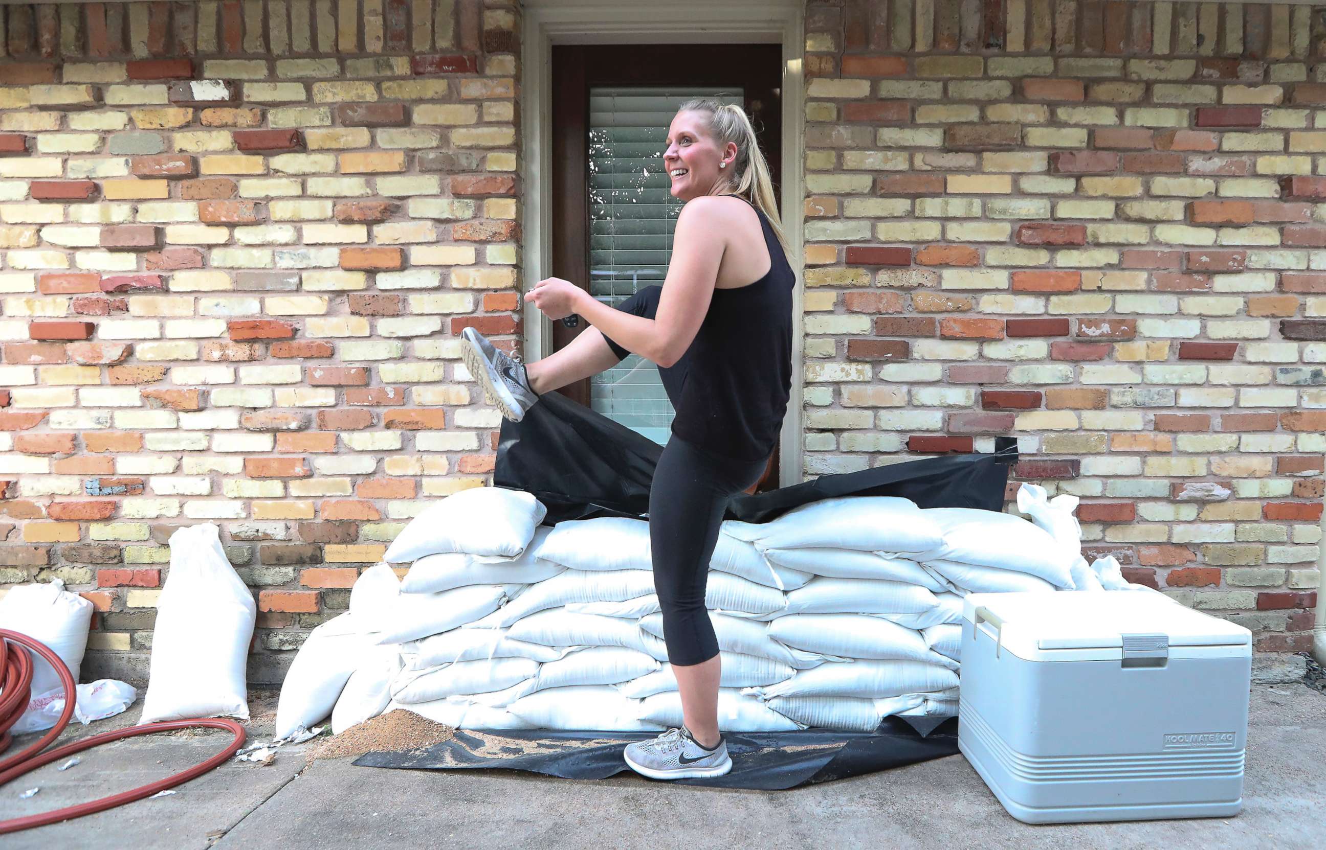 PHOTO: Lacey Williams exits the only door she can by stepping over sandbags that surround her home in Houston Aug. 24, 2017.   