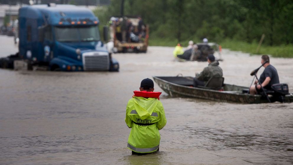 People make their way through a flooded street during the aftermath of Hurricane Harvey, Aug. 29, 2017, in Houston.  Floodwaters have breached a levee south of the city of Houston, officials said Tuesday, urging residents to leave the area immediately. 