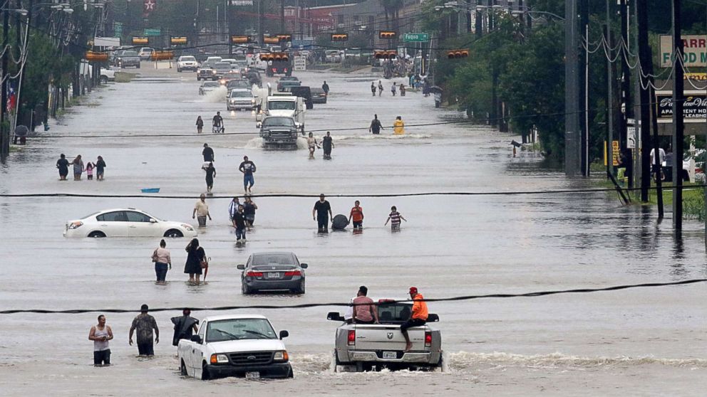 PHOTO: People walk through the flooded waters of Telephone Rd. in Houston on Aug. 27, 2017, as the city battles with tropical storm Harvey and resulting floods.
