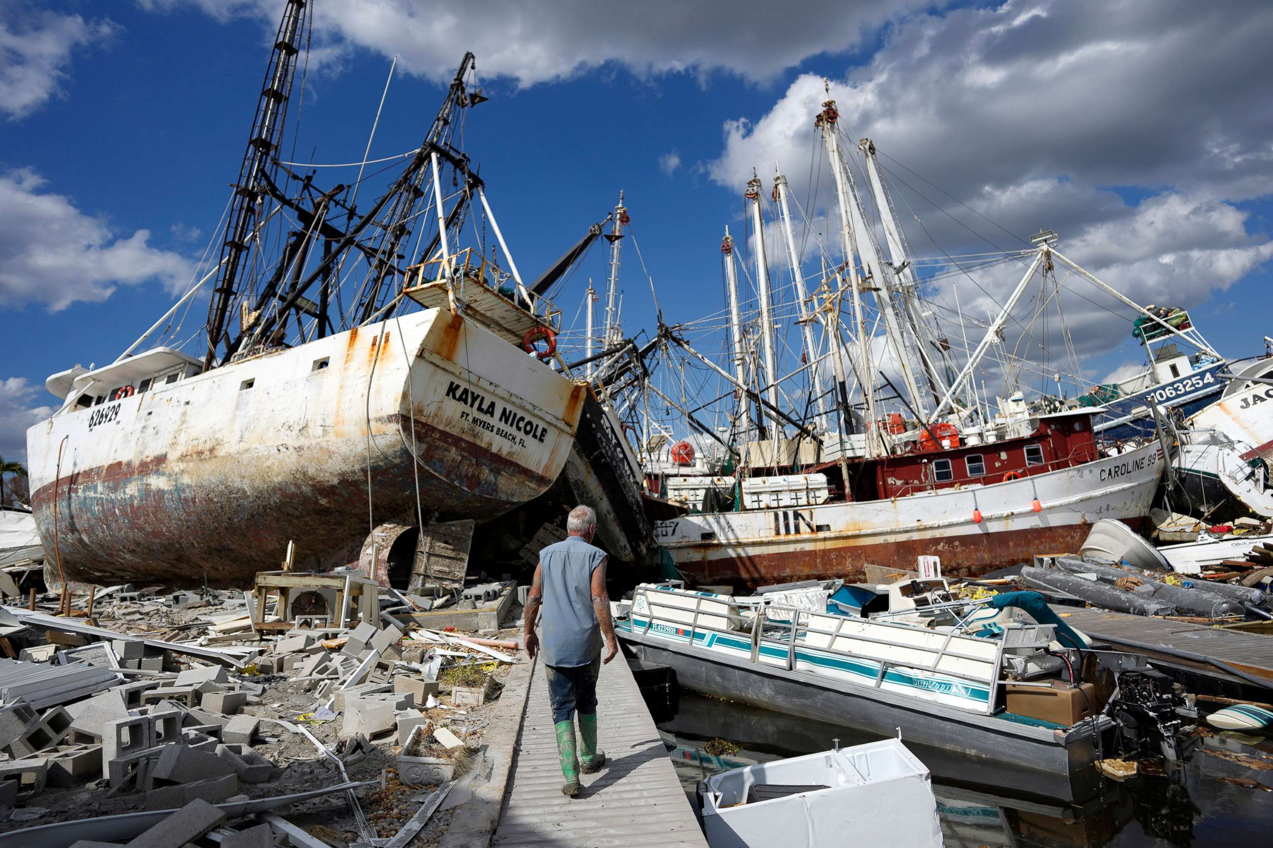 PHOTO: Snowbird Bruce Hickey, 70, walks along the waterfront, now littered with debris including shrimp boats, on San Carlos Island, Fla., Oct. 5, 2022, one week after the passage of Hurricane Ian. 