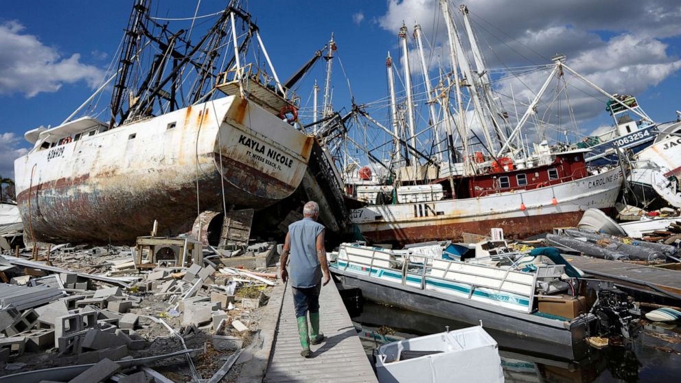 PHOTO: Snowbird Bruce Hickey, 70, walks along the waterfront, now littered with debris including shrimp boats, on San Carlos Island, Fla., Oct. 5, 2022, one week after the passage of Hurricane Ian. 