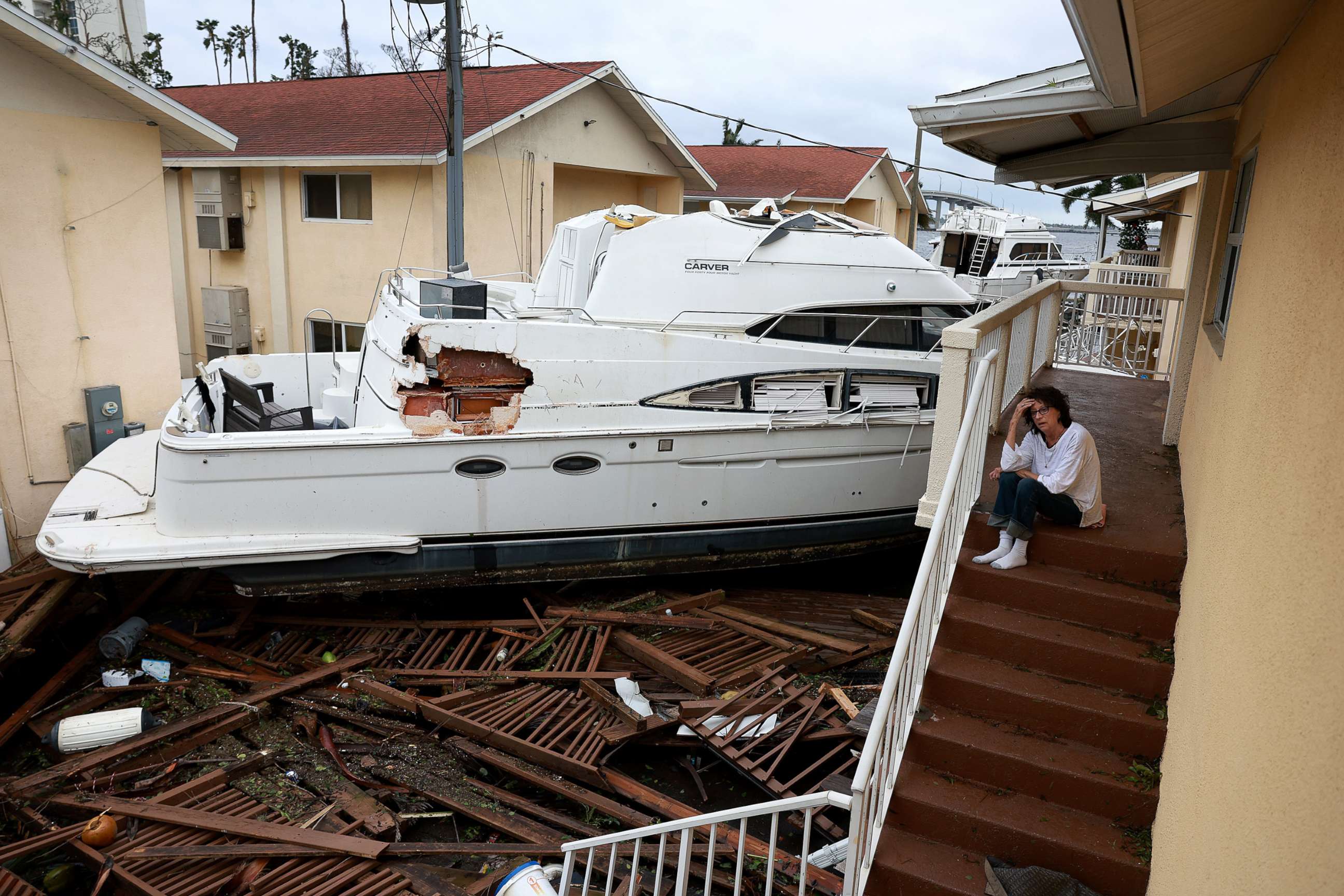 PHOTO: Brenda Brennan sits next to a boat that pushed against her apartment when Hurricane Ian passed through the area on Sept. 29, 2022 in Fort Myers, Fla.