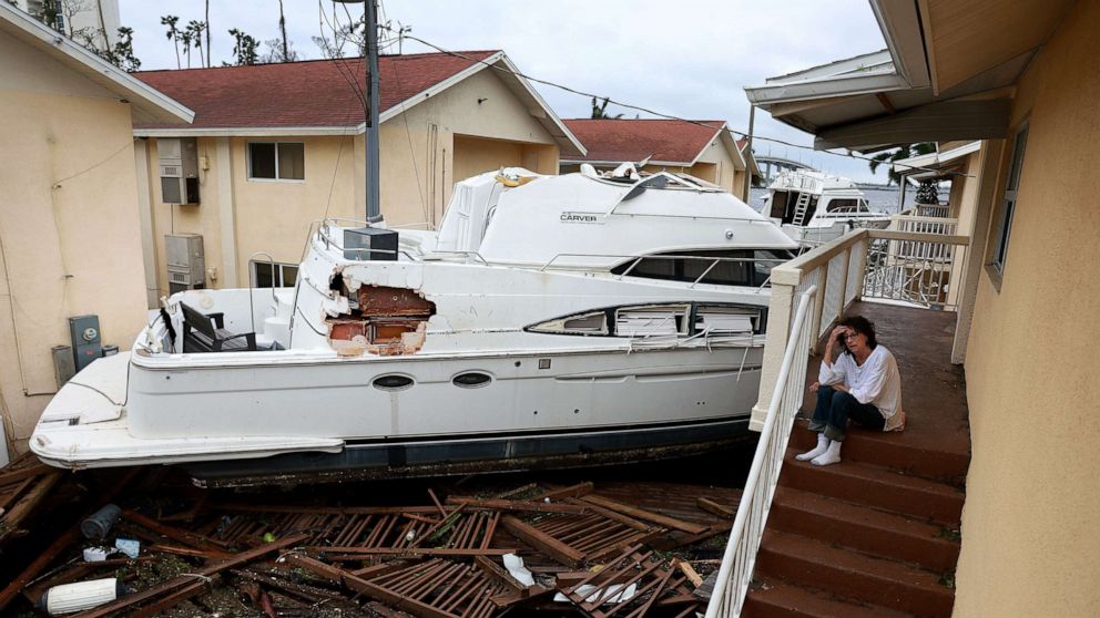 PHOTO: Brenda Brennan sits next to a boat that pushed against her apartment when Hurricane Ian passed through the area on Sept. 29, 2022 in Fort Myers, Fla.