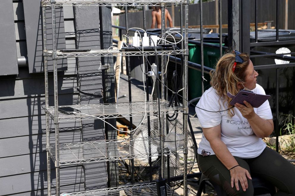 PHOTO: Vanessa Curtis Nosetti charges her phone with others at a charging station set up off a generator at Mayhew Bakery as power continues to be out in most of the city after hurricane Ida ripped through the state, in New Orleans, Sept. 1, 2021.