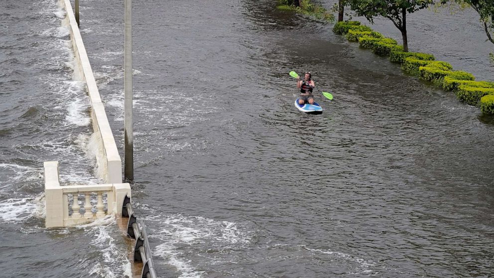 PHOTO: Zeke Pierce rides his paddle board down the middle of a flooded Bayshore Blvd in downtown in Tampa, Fla., Aug. 30, 2023.