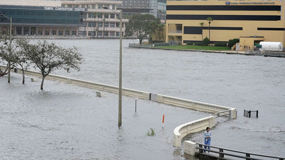 PHOTO: A woman surveys the flooding on Bayshore Blvd., along Old Tampa Bay after winds from Hurricane Idalia pushed water over the sea wall, Aug. 30, 2023, in Tampa, Fla.