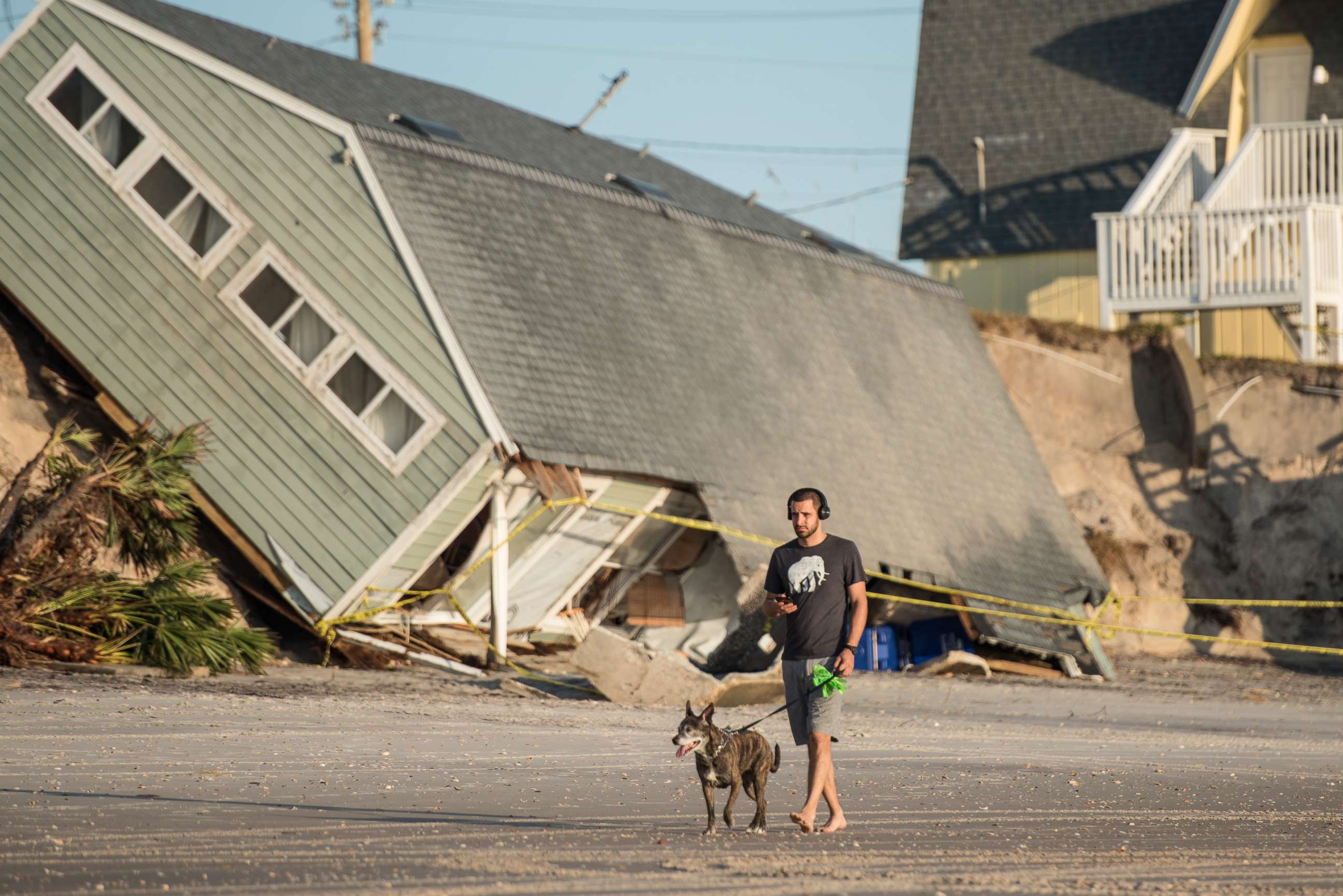 PHOTO: A man walks his dog by a beachfront home destroyed by Hurricane Irma in Vilano Beach, Fla, Sept. 13, 2017.