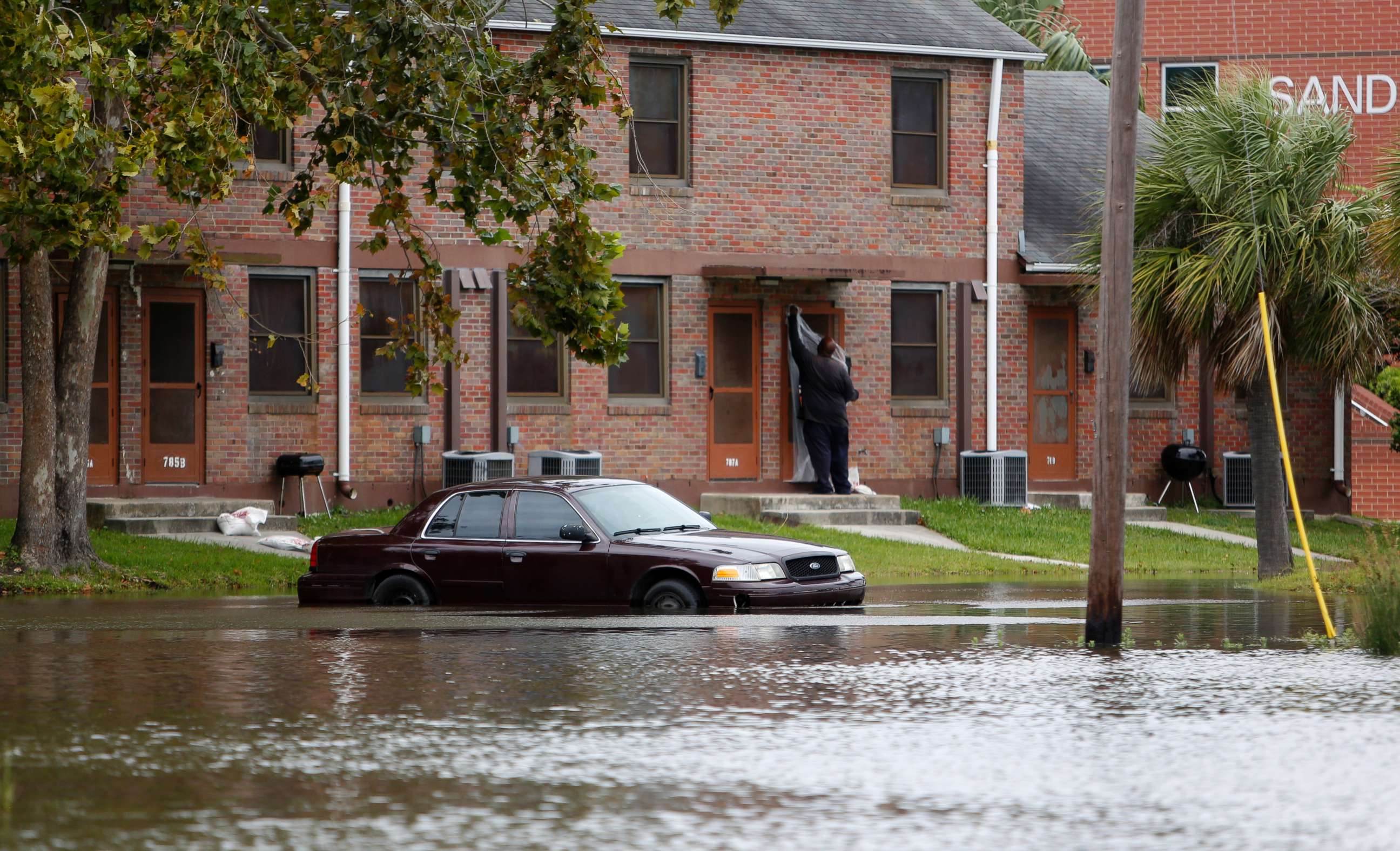 PHOTO: A Charleston, S.C. resident puts plastic up over his apartment door as a car rests in floodwaters near East Bay Street in Charleston, S.C., Sept. 10, 2017.