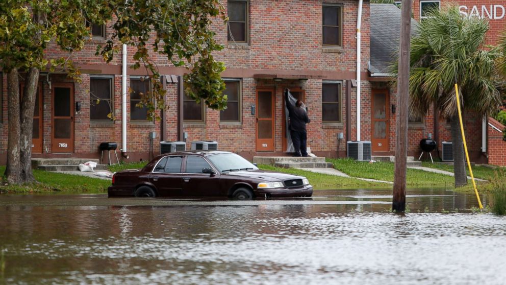PHOTO: A Charleston, S.C. resident puts plastic up over his apartment door as a car rests in floodwaters near East Bay Street in Charleston, S.C., Sept. 10, 2017.