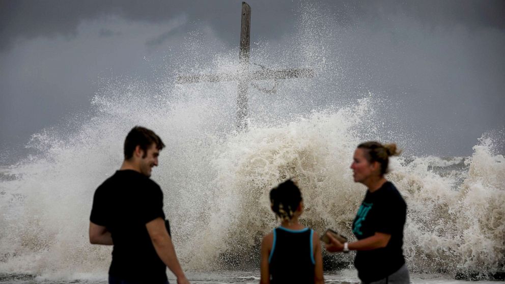 PHOTO: People talk as waves wash ashore and the outer bands of Hurricane Laura bring winds and rain, Aug. 26, 2020, in High Island.