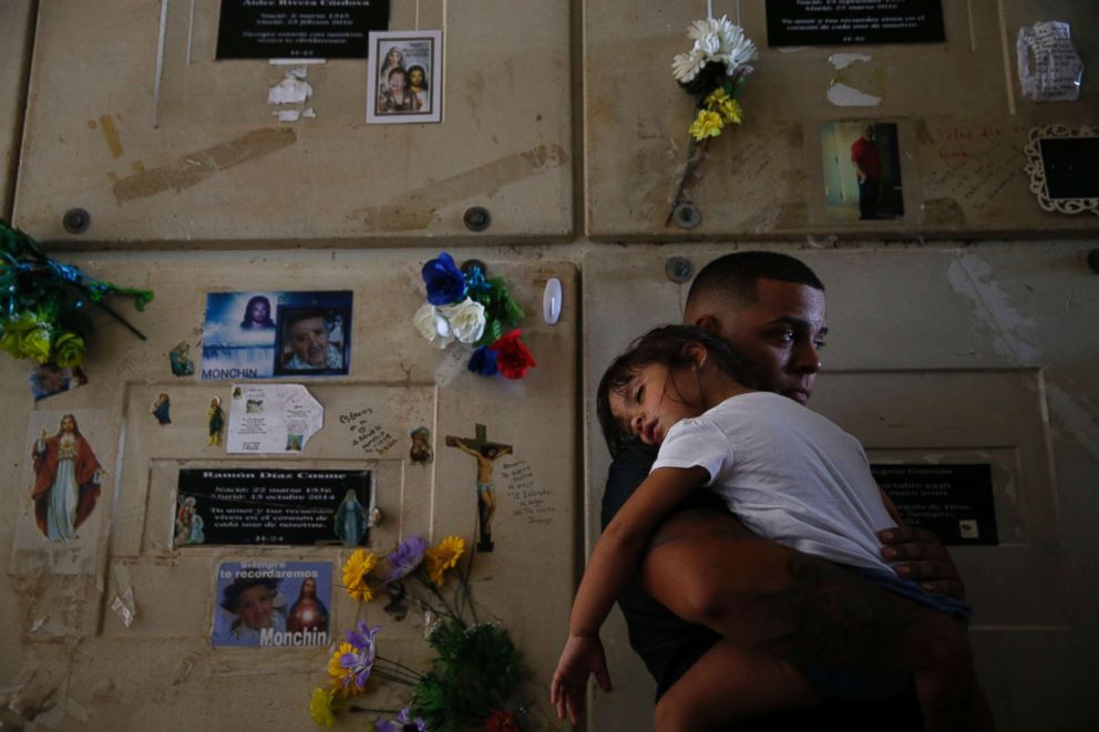 PHOTO: Orlando Gonzalez holds his daughter Nahielys as they attend the funeral of their neighbor Victor Ruiz Ramos in Corozal, Puerto Rico on Oct. 2, 2017.