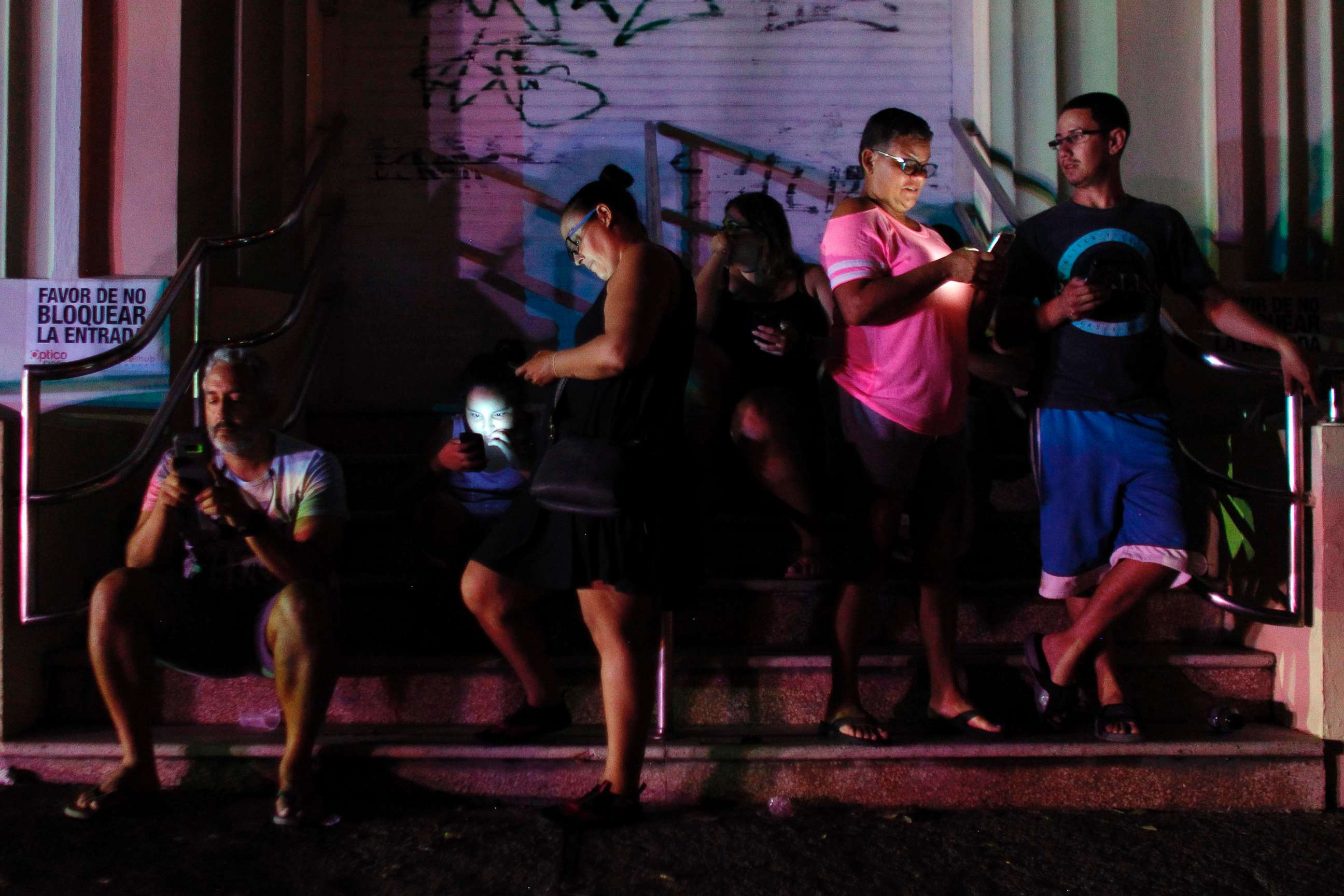 PHOTO: People use their cell phones at night in one of the few places with cell signal in San Juan, Puerto Rico, Sept. 25, 2017, where a 7pm-6am curfew has been imposed following impact of Hurricane Maria on the island. 