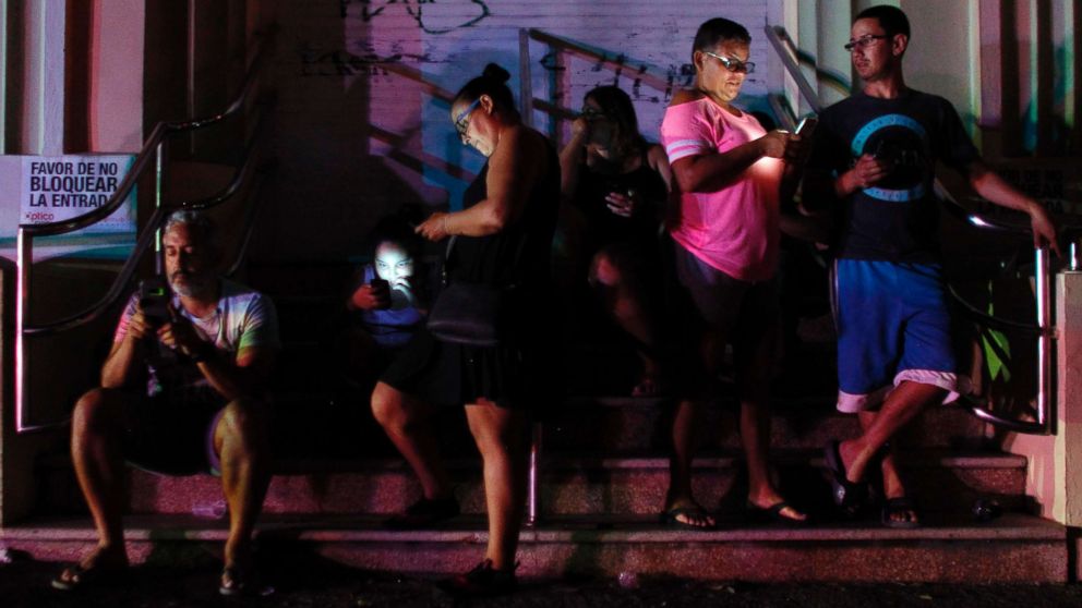 People use their cell phones at night in one of the few places with cell signal in San Juan, Puerto Rico, Sept. 25, 2017, where a 7pm-6am curfew has been imposed following impact of Hurricane Maria on the island.