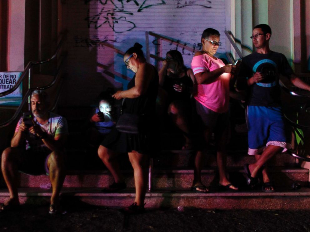 PHOTO: People use their cell phones at night in one of the few places with cell signal in San Juan, Puerto Rico, Sept. 25, 2017, where a 7pm-6am curfew has been imposed following impact of Hurricane Maria on the island.