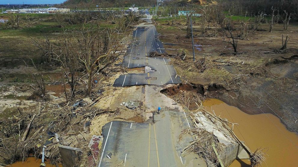 PHOTO: A man rides his bicycle through a damaged road in Toa Alta, west of San Juan, Puerto Rico, Sept. 24, 2017, following the passage of Hurricane Maria.