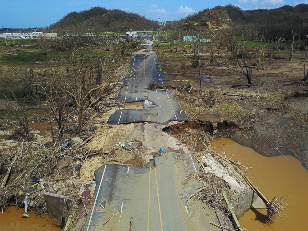 PHOTO: A man rides his bicycle through a damaged road in Toa Alta, west of San Juan, Puerto Rico, Sept. 24, 2017, following the passage of Hurricane Maria.
