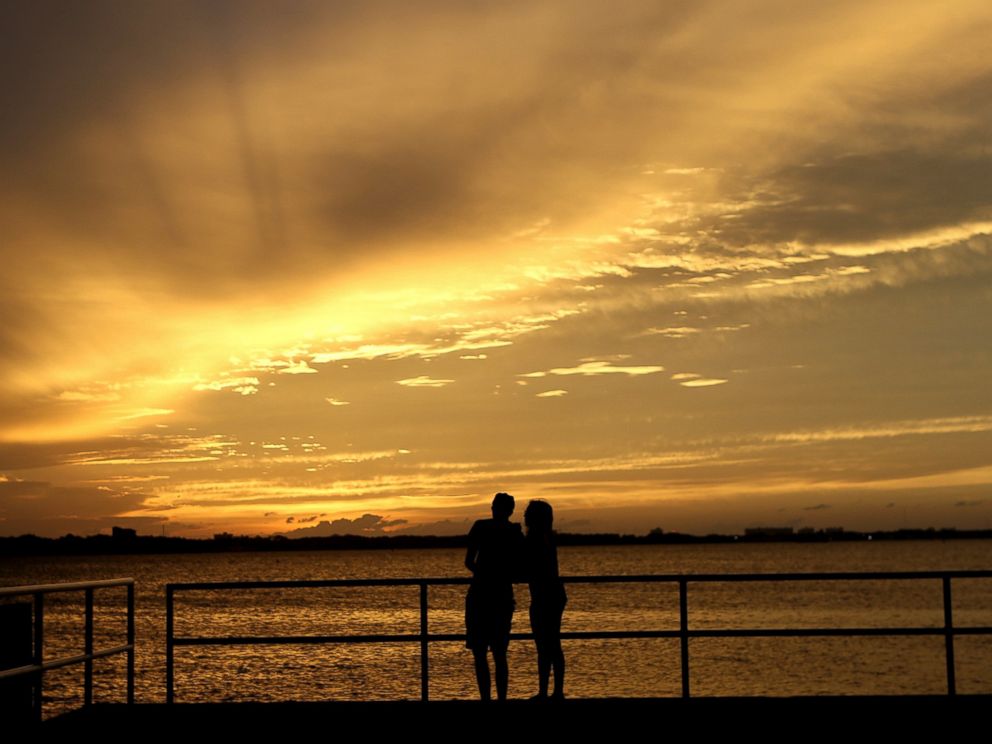 PHOTO: A couple is silhouetted against the sunset at the St. Andrews Marina in Panama City, Fla., Tuesday, Oct. 9, 2018, ahead of Hurricane Michael.