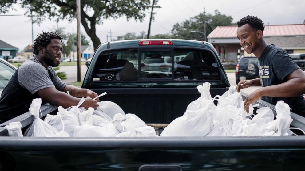 PHOTO: Percy Harrison (L) and Jeramie Moliere load sandbags into the back of a truck to bring to people who live in the neighborhood surrounding their church in preparation for Hurricane Nate in New Orleans, Oct. 7, 2017.