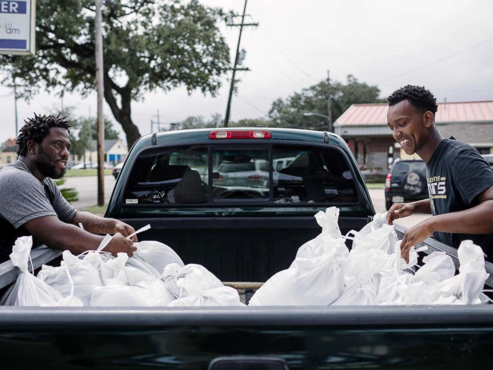 PHOTO: Percy Harrison (L) and Jeramie Moliere load sandbags into the back of a truck to bring to people who live in the neighborhood surrounding their church in preparation for Hurricane Nate in New Orleans, Oct. 7, 2017.