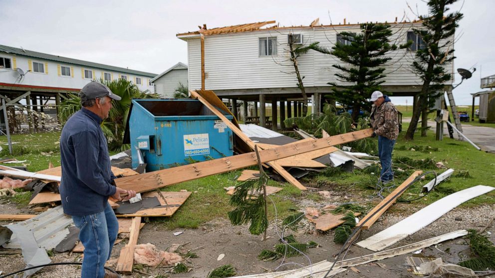 PHOTO: Mark Andollina, left, and Shane Holder, remove part of a roof damaged by Hurricane Zeta from the road at the Cajun Tide Beach Resort in Grand Isle, La., Oct. 30, 2020.