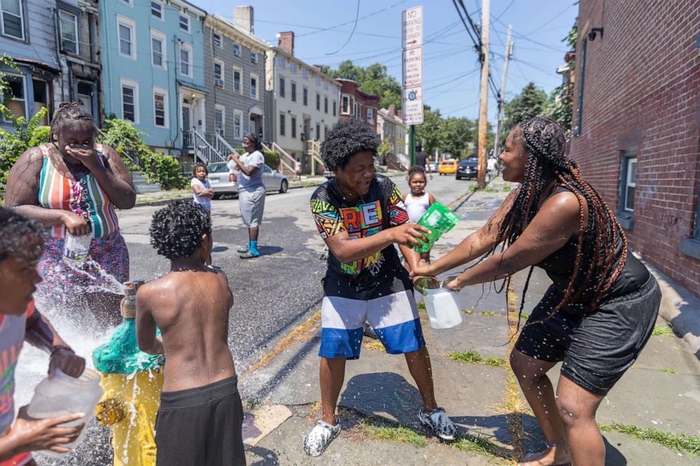 PHOTO: People play in front of an open fire hydrant during hot weather in Newburgh, N.Y., July 19, 2022.
