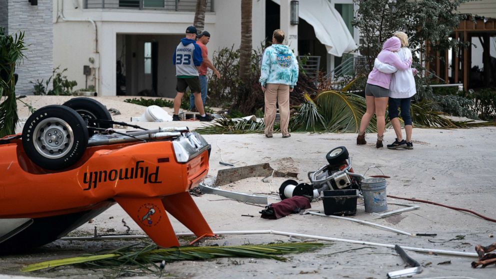 PHOTO: People hug as they survey property damage caused by Hurricane Ian, Sept. 29, 2022, in Bonita Springs, Florida.