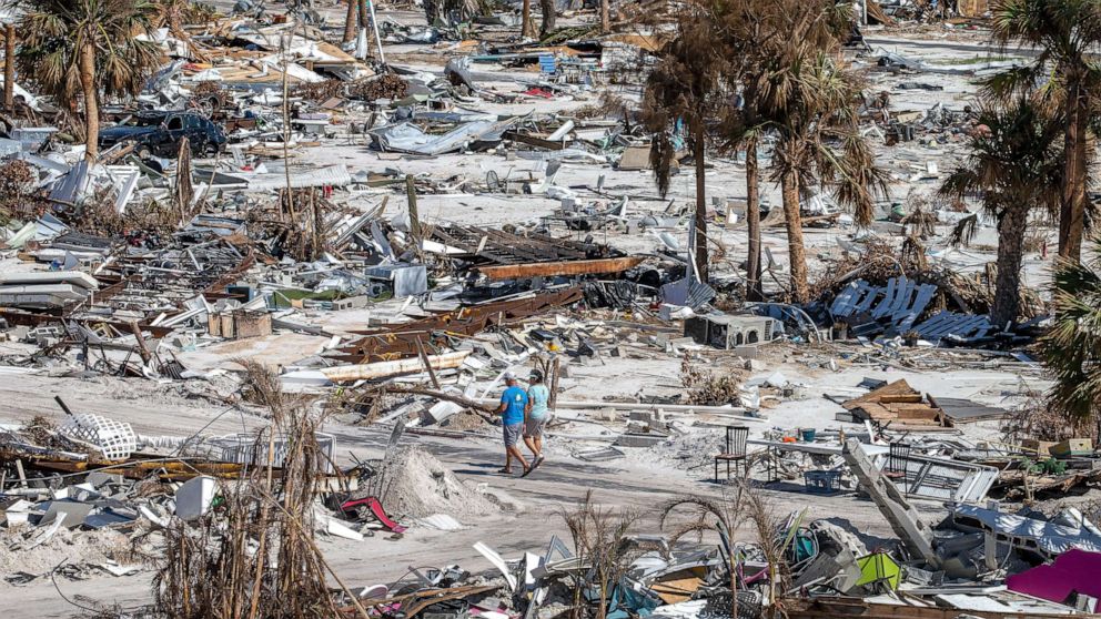 PHOTO: People walk among the debris in Red Coconut RV Park nearly a month after Hurricane Ian made landfall, Oct. 27, 2022, in Fort Myers beach, Fla.