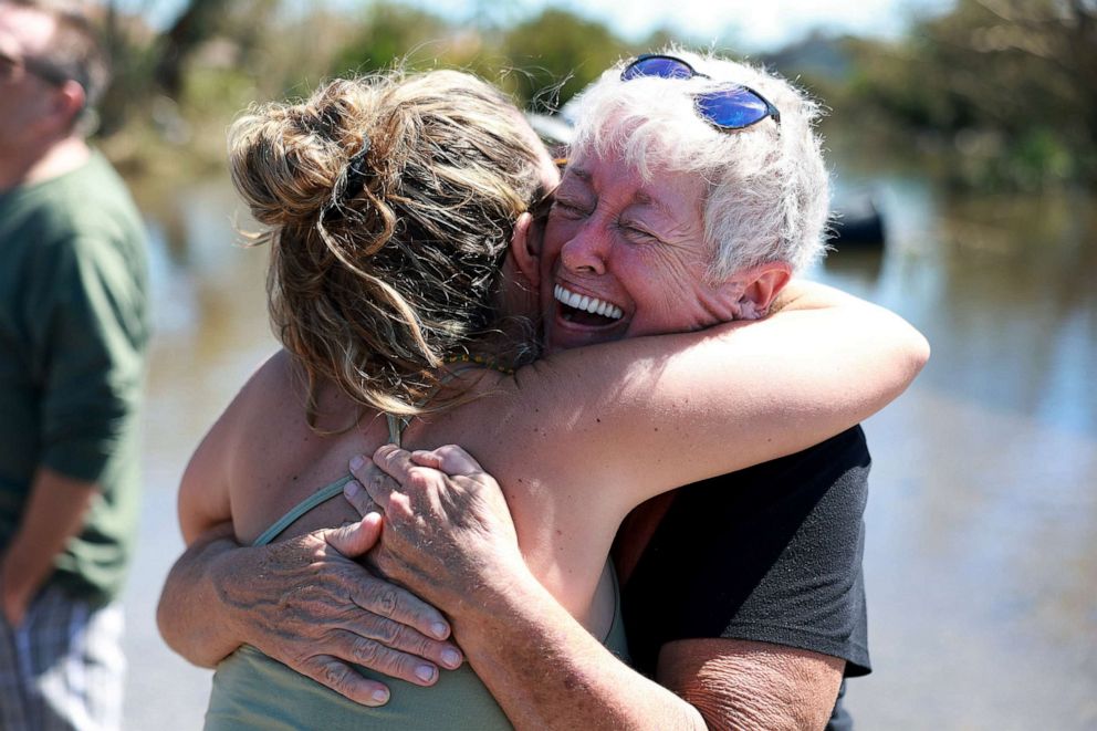 PHOTO: Sue Lepisto hugs her neighbor after they saw each other while visiting their homes, which were flooded by six feet of water, following Hurricane Ian, Sept. 30, 2022, in Fort Myers, Fla.