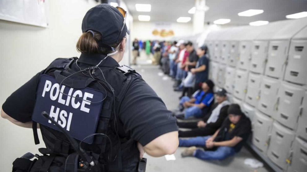 PHOTO: This image released by the US Immigration and Customs Enforcement (ICE) shows a Homeland Security Investigations (HSI) officer guarding suspected illegal aliens on August 7, 2019.