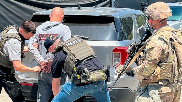 National Guardsmen accompany ICE officers while they detain a man in Los Angeles.