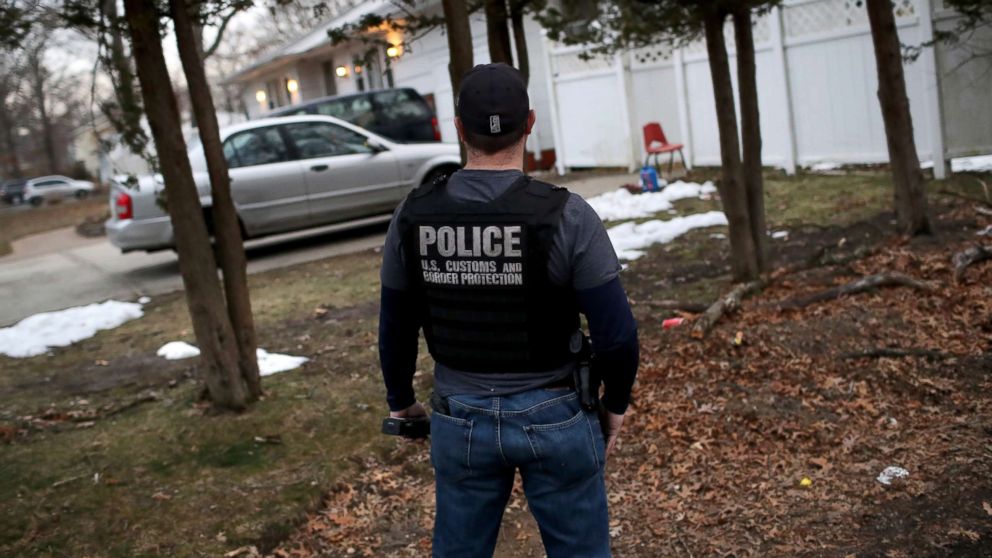A Customs and Border Protection officer watches a house as Homeland Security Investigations (HSI) ICE agents detain a suspected MS-13 gang member and Honduran immigrant at his home, March 29, 2018, in Brentwood, New York.