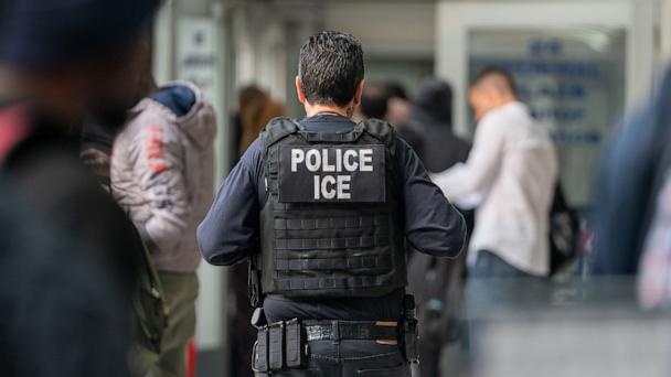 An ICE agent monitors hundreds of asylum seekers being processed upon entering the Jacob K. Javits Federal Building on June 6, 2023 in New York City.