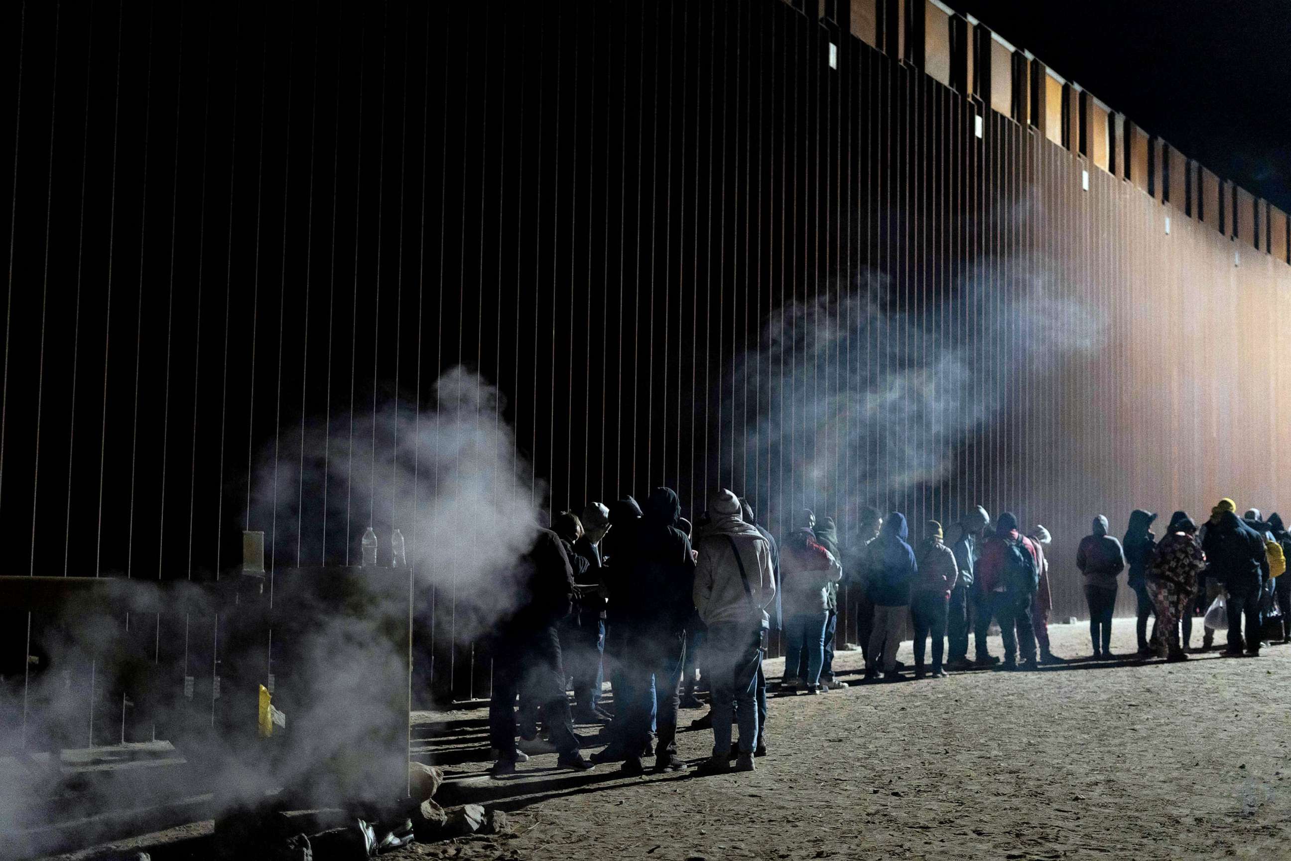 PHOTO: Asylum-seekers line up to be processed by US Customs and Border Patrol agents at a gap in the US-Mexico border fence near Somerton, Arizona, Dec. 26, 2022.