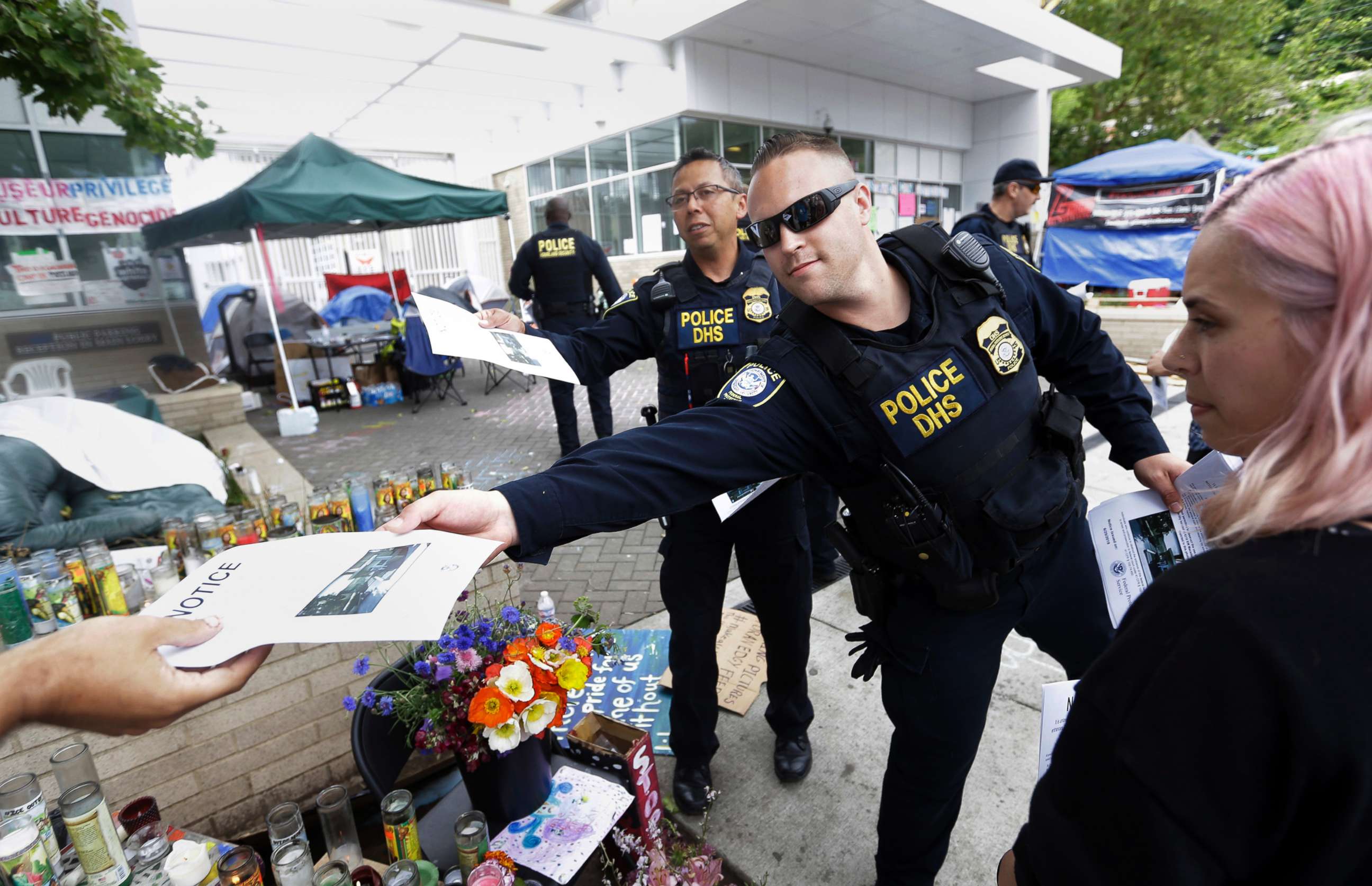 PHOTO: Law enforcement officers hand out notices to vacate to demonstrators at a protest camp on property outside the U.S. Immigration and Customs Enforcement office in Portland, Ore., June 25, 2018.