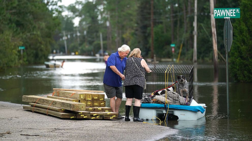 PHOTO: A couple uses a paddle boat to transport their dogs through a flooded neighborhood on Aug. 30, 2021 in Kiln, Miss.