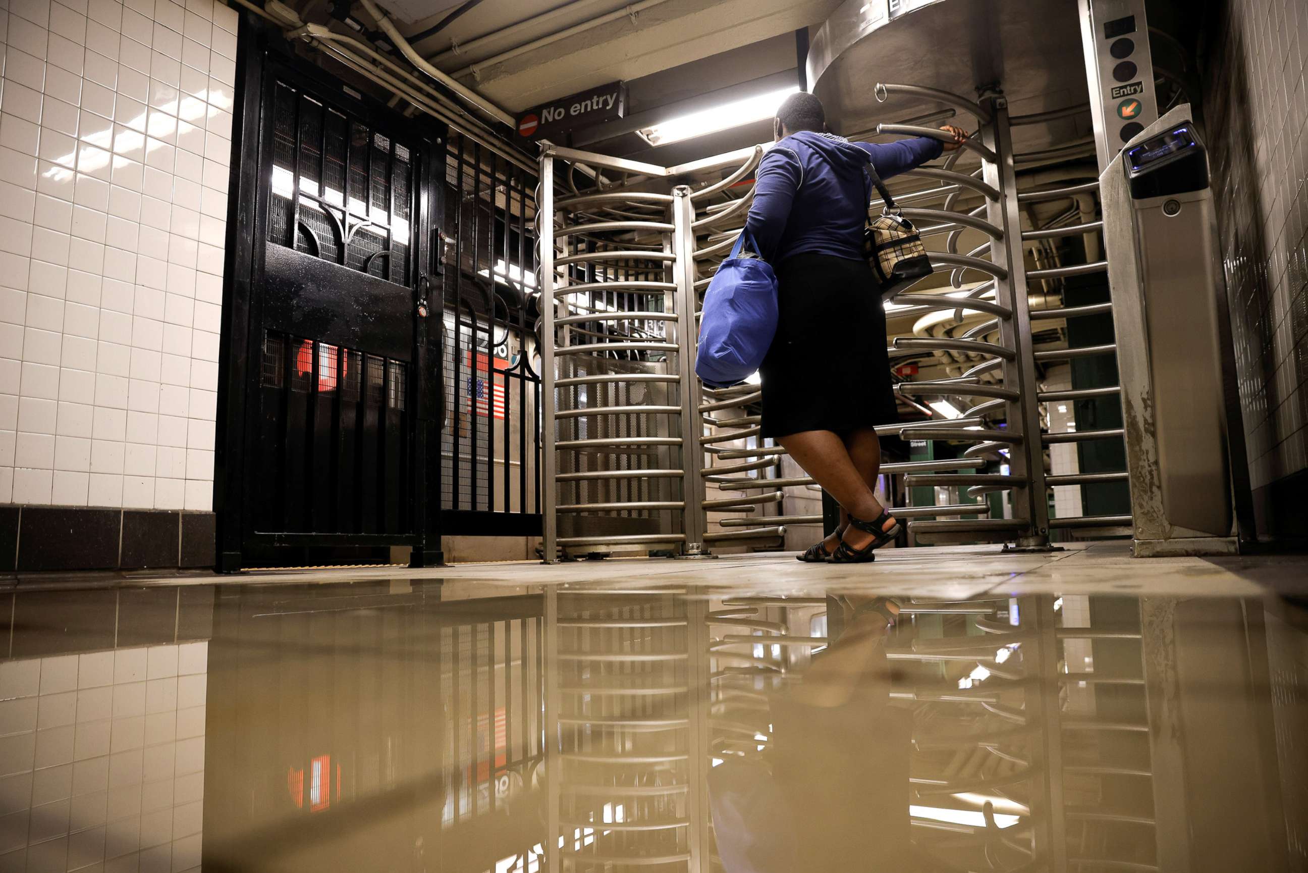 PHOTO: A woman waits by the entrance of Rector Street subway station as the service is delayed after heavy rainfall in New York City, Sept. 2, 2021.