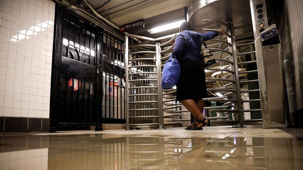 PHOTO: A woman waits by the entrance of Rector Street subway station as the service is delayed after heavy rainfall in New York City, Sept. 2, 2021.