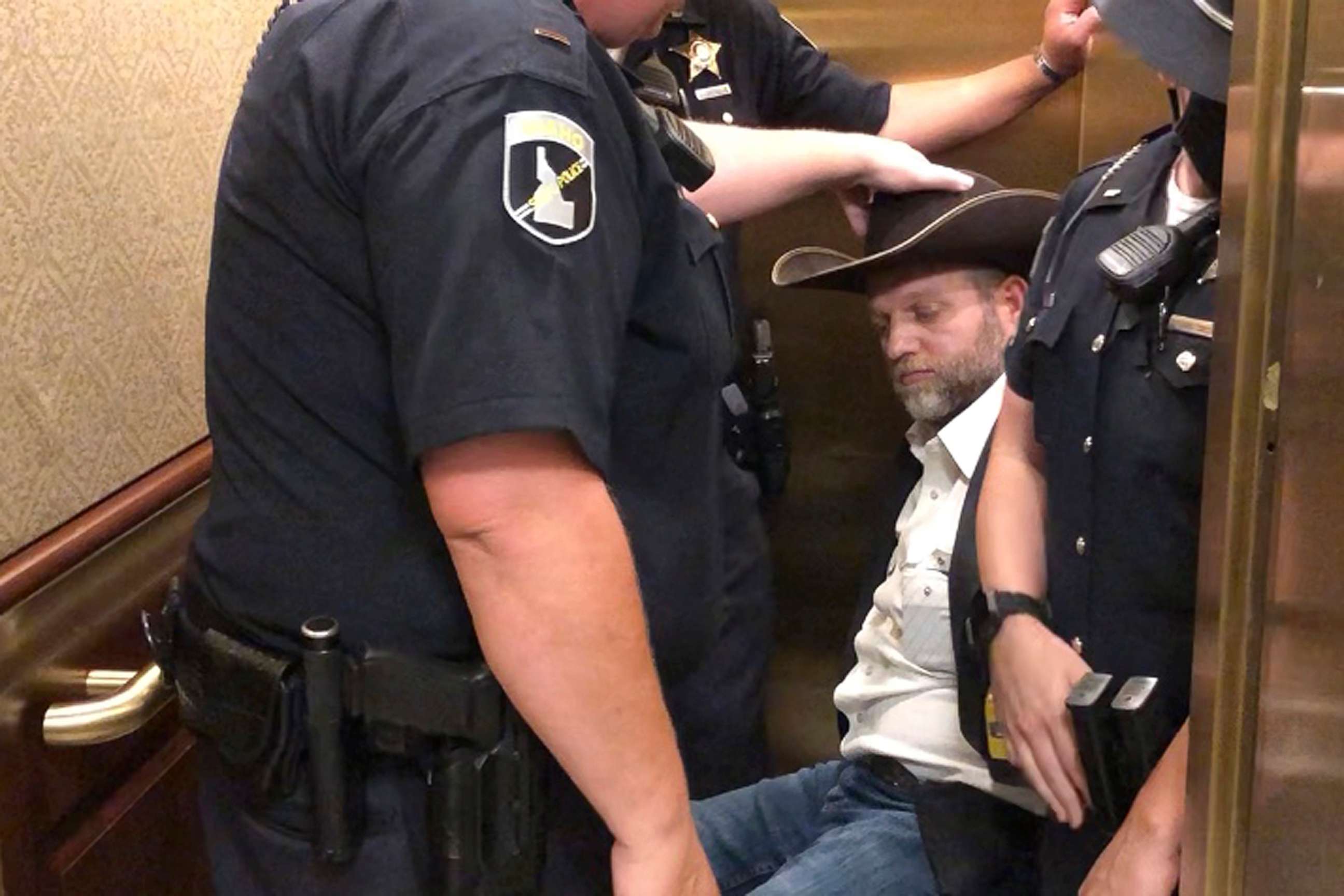 PHOTO: This image taken from video shows anti-government activist Ammon Bundy, rear, being wheeled into an elevator in a chair following his arrest at the Idaho Statehouse in Boise, Idaho, Aug. 25, 2020.